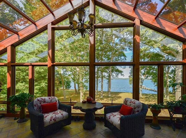 A cathedral sunroom with a view of surrounding large trees and water.